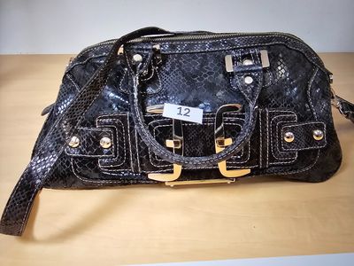 black leather handbag on a wooden table with a price tag on it