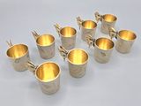 six silver cups are lined up in a row on a white surface