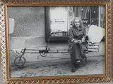 an old photo of a man sitting on a bench with a bike attached to it