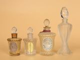 trois flacons de parfum en verre sont alignés sur une surface beige