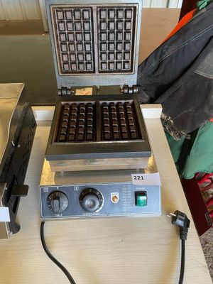 un gaufrier posé sur une table à côté d'une boîte de beignets