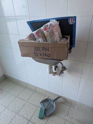 une boîte de papier toilette posée par terre à côté d'une poubelle