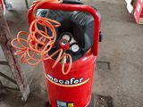 a red air compressor sitting on a cart in a warehouse