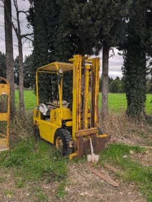 two yellow forklifts parked next to each other in a field