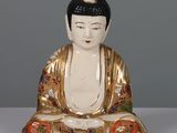 une statue représentant une personne assise sur une table