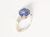a close up of a blue sapphire and diamond ring on a white surface