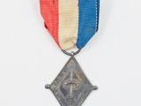 une vieille médaille sur fond blanc, accompagnée d'un ruban rouge, blanc et bleu