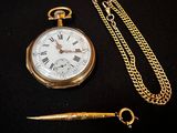 une montre de poche en or et une chaîne sur un fond noir