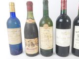 six bottles of wine are lined up in a row on a white surface