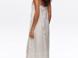 woman wearing a white dress and sandals standing in front of a white background