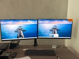 deux écrans d'ordinateur posés sur un bureau, avec un clavier et un ordinateur portable