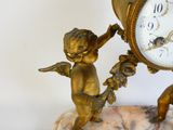 a small statue of a boy holding a clock on a rock
