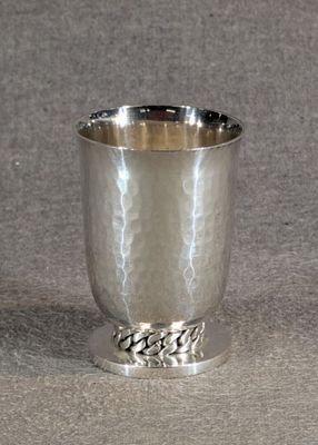 une coupe en argent entourée d'une chaîne, posée sur une table