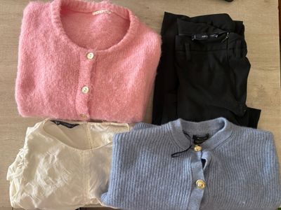 three pairs of sweaters and pants sitting on a table next to a pair of shoes
