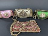 three indian handbags and a purse on a black background