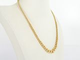 a gold necklace on a mannequin torso with a white background