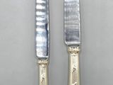 pair of silver plated knifes with handles on a white surface