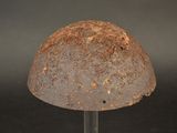 an old rusty helmet sitting on a metal stand