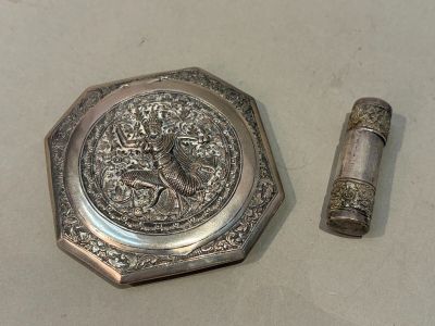 un petit objet argenté posé à côté d'un briquet sur une table