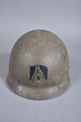 un vieux casque orné d'un autocollant, posé sur une surface blanche