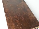 an old brown book sitting on top of a white table