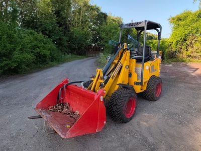 un petit tracteur jaune garé sur le bord de la route