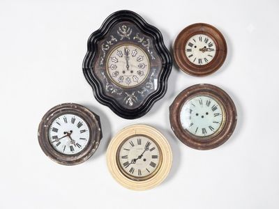 cinq horloges différentes posées sur une surface blanche, sur fond blanc
