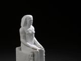 une image représentant une statue d'une femme assise sur un bloc de pierre