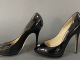 pair of women ' s black high heeled shoes on a grey surface