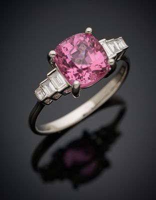 une bague sertie d'un saphir rose et de diamants, posée sur un fond noir