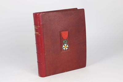 an old book with a red cover and a medal on it