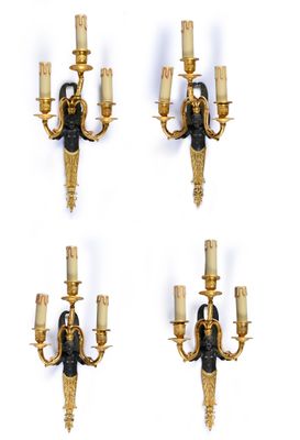 four gold and black wall sconces with candles on each of them