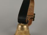 clochette en laiton avec un cordon en cuir noir sur fond gris