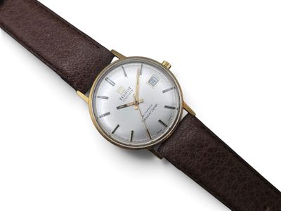 a close up of a watch on a white surface with a brown strap