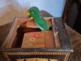 a small green bird sitting on top of a wooden box