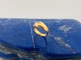 un gros plan d'une bague en or posée sur une pierre bleue
