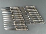 six silverplated knives and six knives on a table