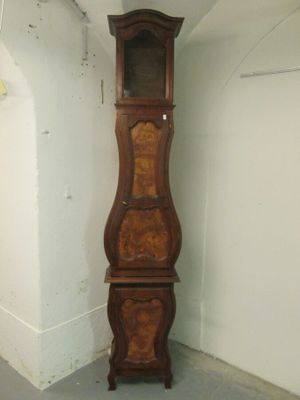 une grande horloge comtoise en bois, dans un coin de la pièce