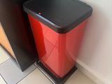 a red trash can sitting next to a black trash can