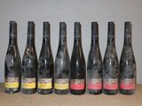 six bouteilles de vin alignées sur une table, avec un mur en arrière-plan