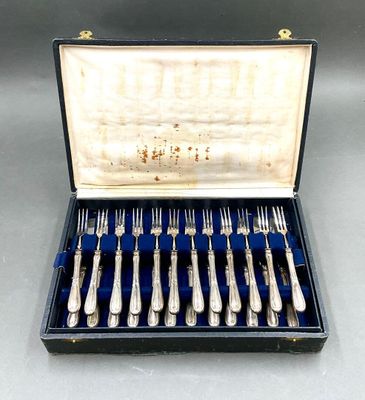 un service d'argenterie dans un coffret doublé de velours bleu, posé sur une table