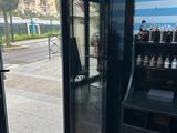 un réfrigérateur noir posé devant une porte vitrée