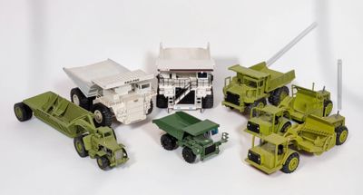 Plusieurs véhicules militaires et camions miniatures sont alignés sur une surface blanche