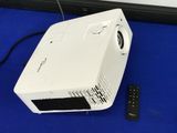 a white projector sitting on a blue surface next to a remote control