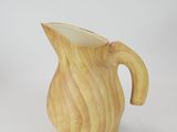 a wooden pitcher that is sitting on a white surface