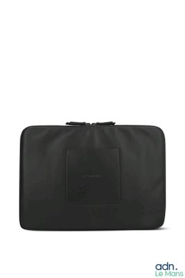 une trousse de toilette noire posée sur une surface blanche