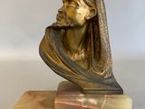 statue d'un homme portant un turban, posée sur un socle en marbre