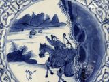 blue and white plate with a picture of a man riding a horse