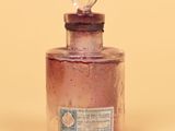 a small glass bottle with a clear lid on a yellow surface