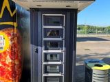 un distributeur automatique de pizzas et une poubelle dans un parking